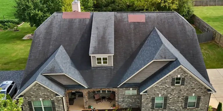 Heavy Moss Growth on Roof | Dom Roofing & Restoration A roof in bad condition with heavy moss growth and dark algae streaks on the shingles, signaling the need for a professional roof inspection.