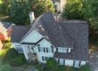 Aerial view of a completed gray shingle roof on a white home