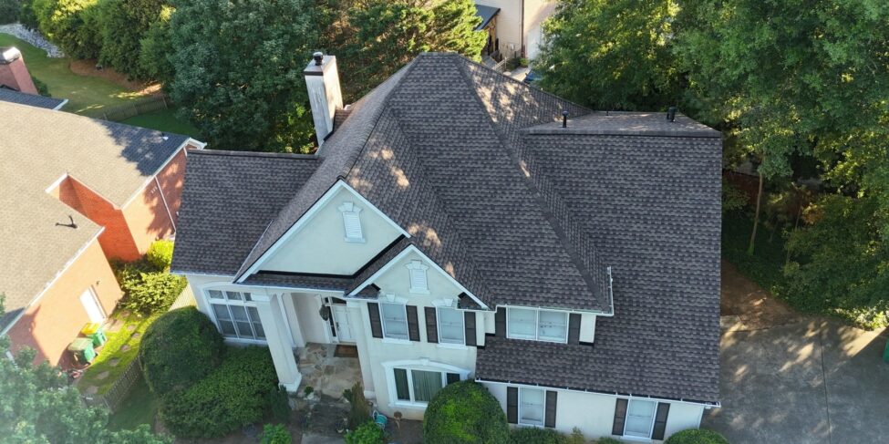 Aerial view of a completed gray shingle roof on a white home