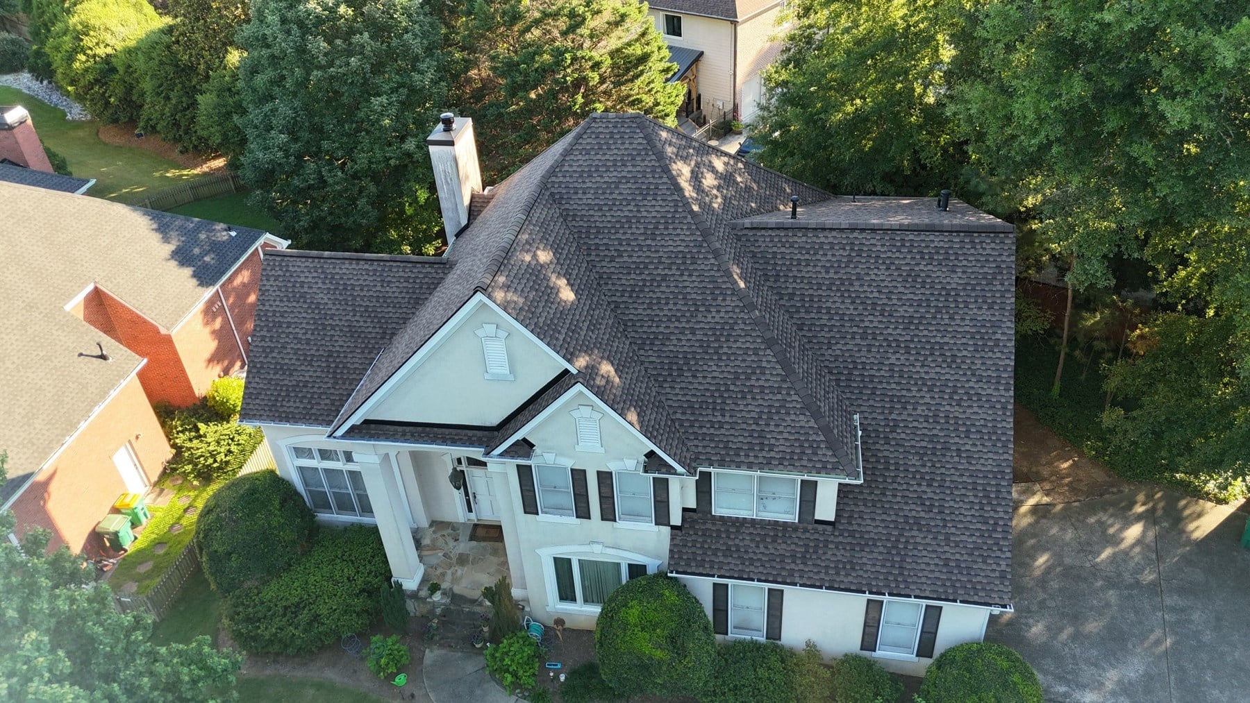 dom-real-class4-01 Aerial view of a completed gray shingle roof on a white home