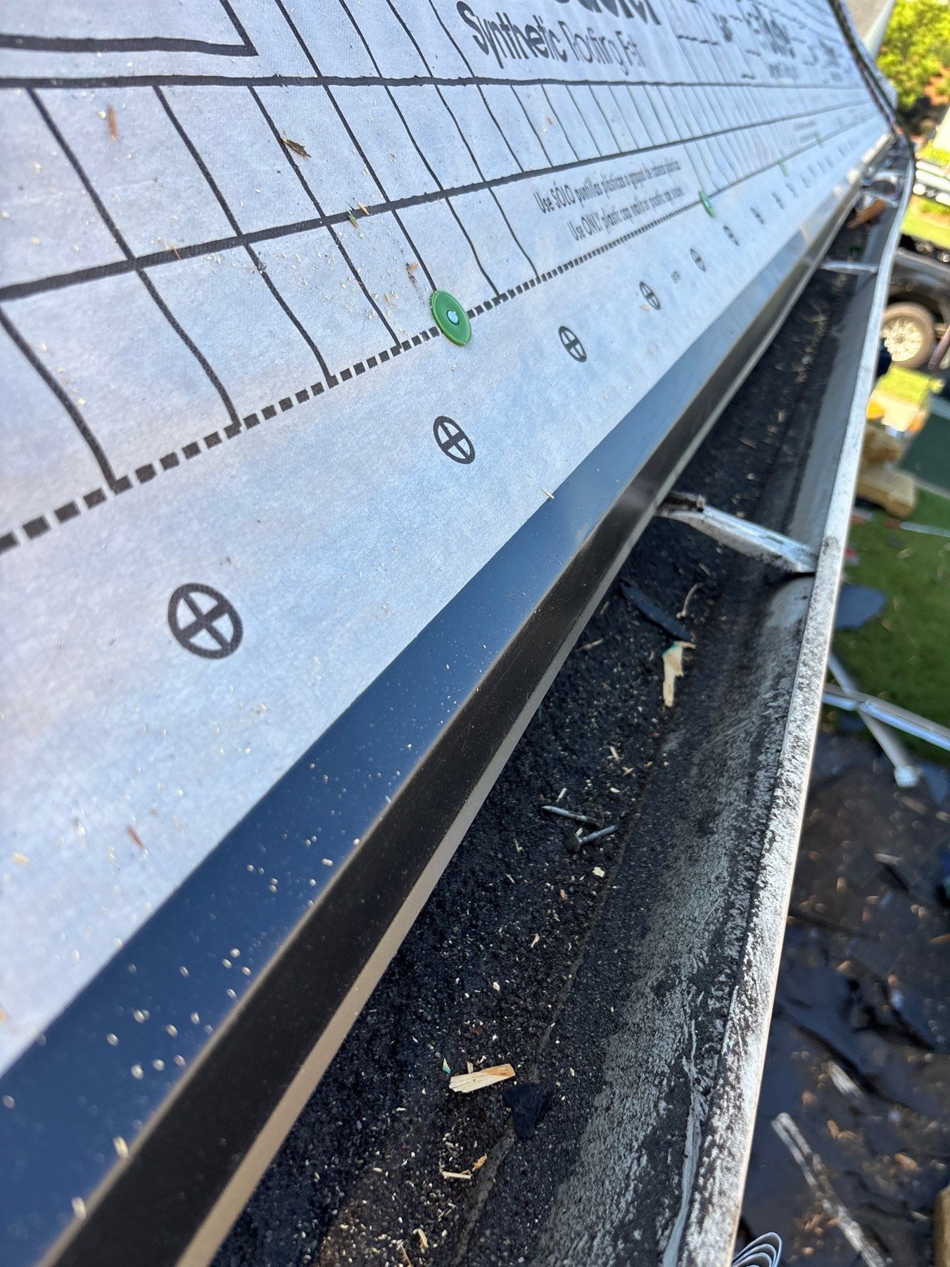 dom-real-drip-01 Metal drip edge along an eave beside a gutter and synthetic underlayment