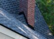 Metal flashing at the base of a brick chimney on a shingle roof
