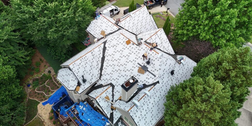 Aerial view of a roof covered with synthetic underlayment during installation
