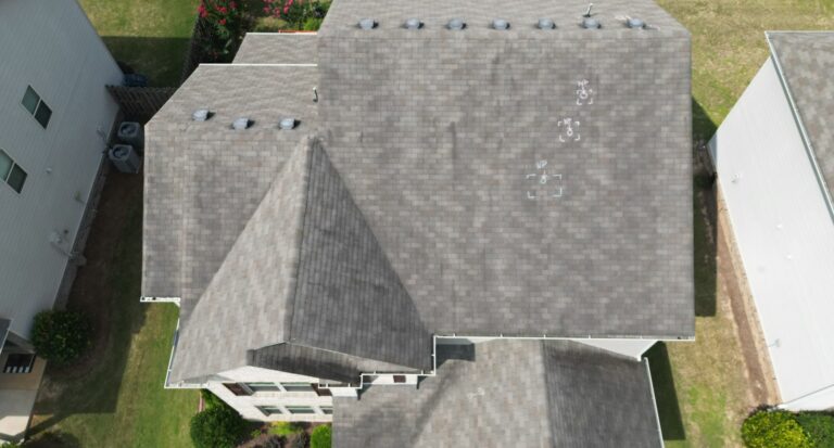 Aerial inspection photo of an asphalt shingle roof with dark streaks and uneven discoloration
