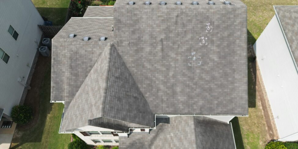 Aerial inspection photo of an asphalt shingle roof with dark streaks and uneven discoloration